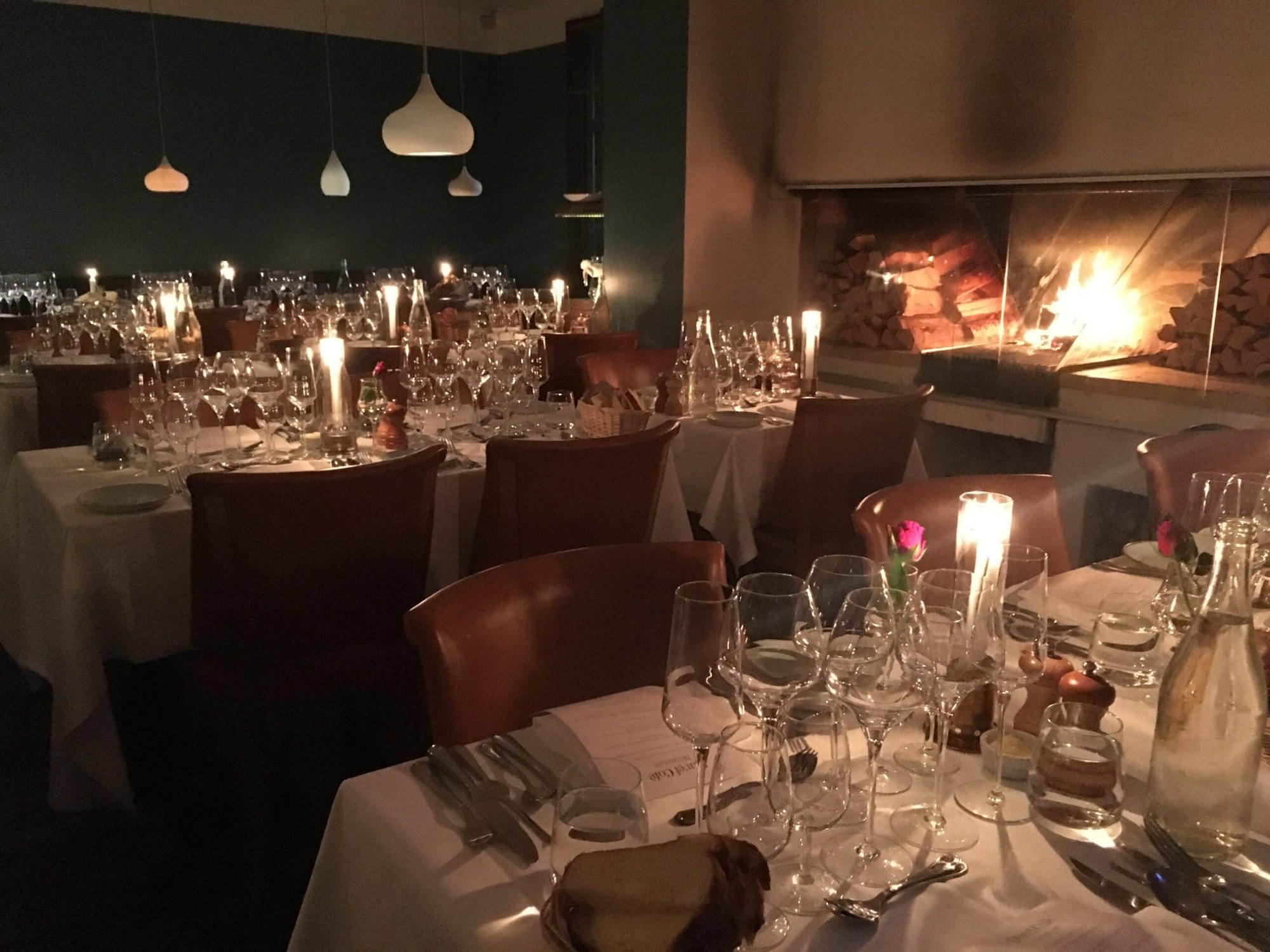 Festdukade bord med levande ljus vid brasan i Duvel Cafés matsal